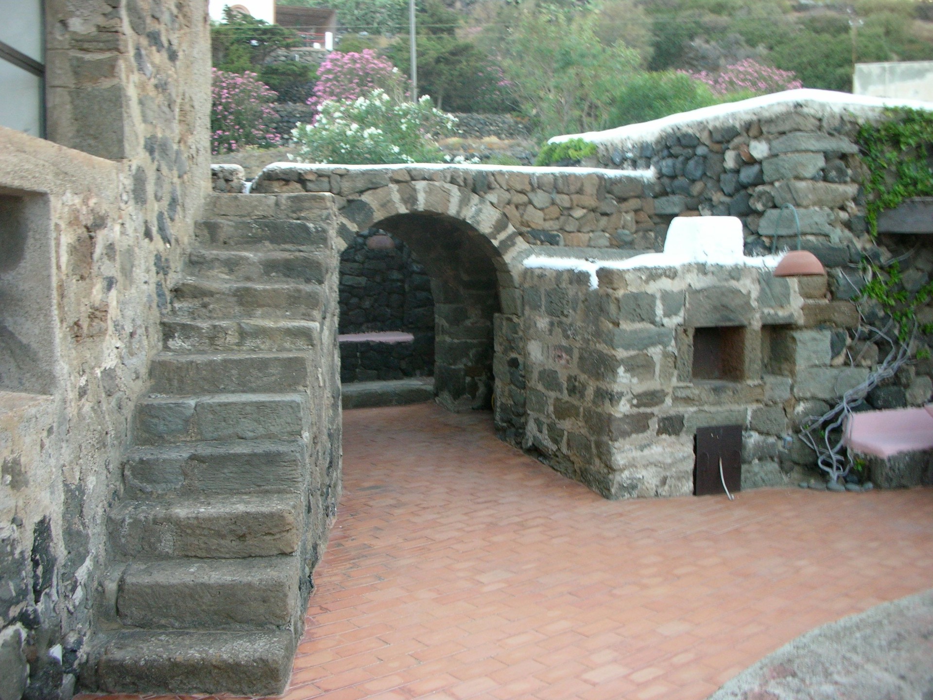 Outdoor wood-fired stone oven with arched portico