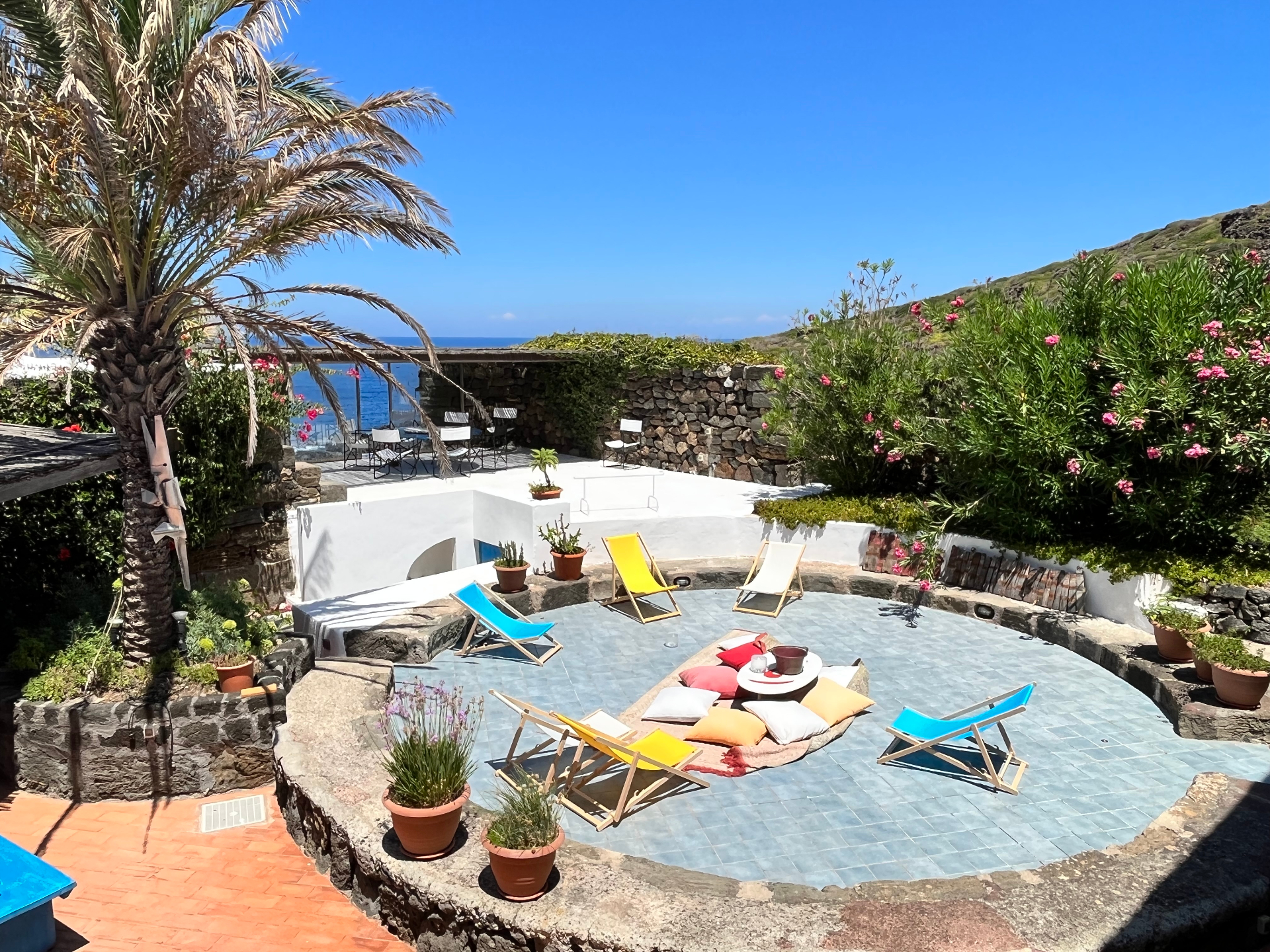 Central piazza with deckchairs, palm tree and sea view from the Royal Suite